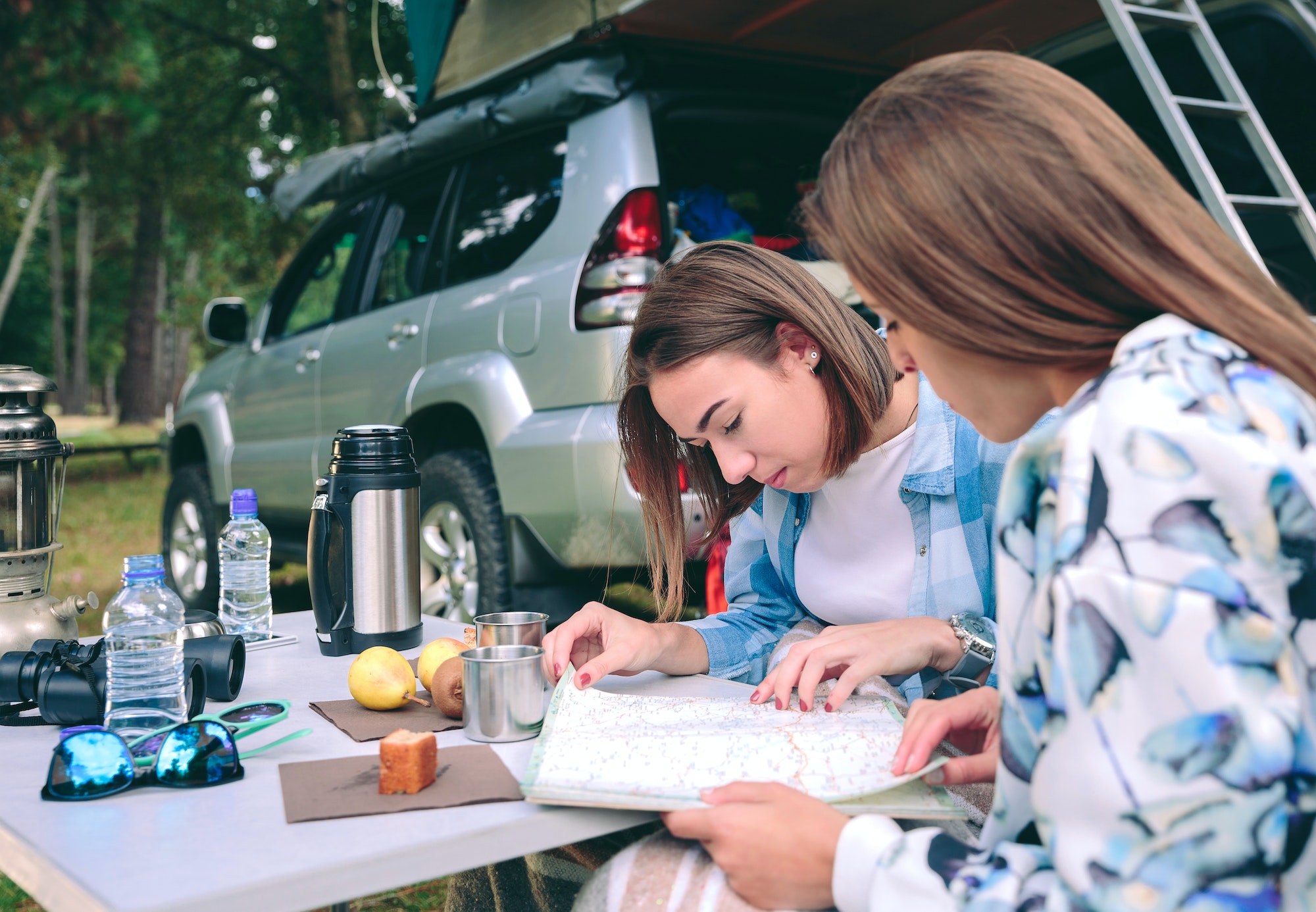 Young women looking road map with 4x4 on background