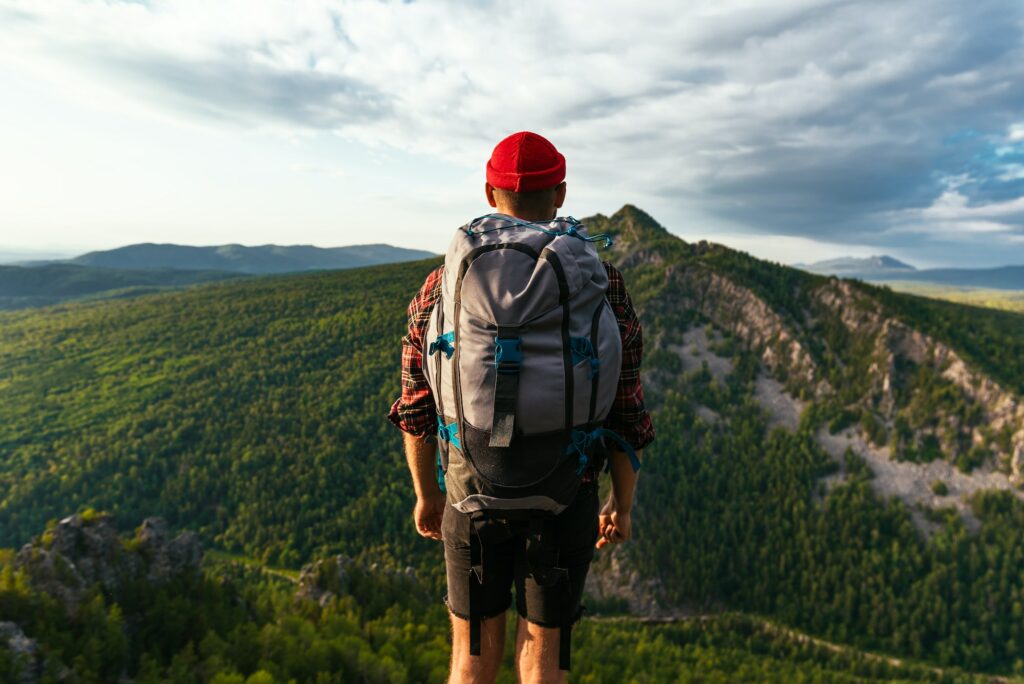 A tourist with a backpack is standing on the top of the mountain