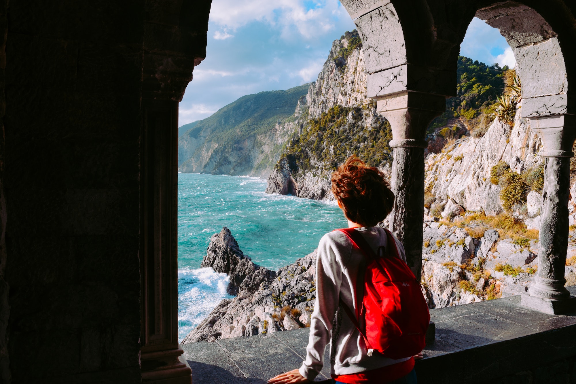 Female tourist with pink backpack looking at the beauty of Mediterranean sea at Cinque Terre