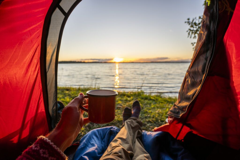 Man camping in Estonia, watching sunset lying in tent