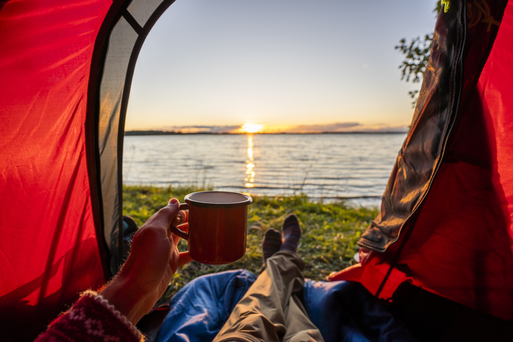 Man camping in Estonia, watching sunset lying in tent