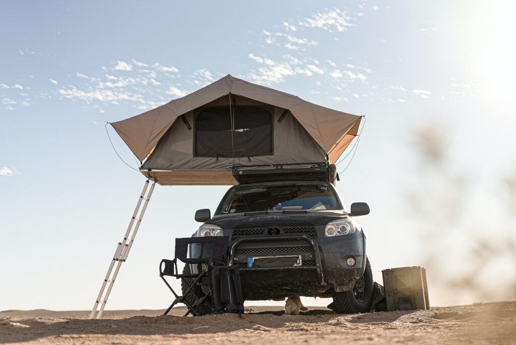 Rooftop tent for camping on the roof rack of an off-road SUV car in a desert
