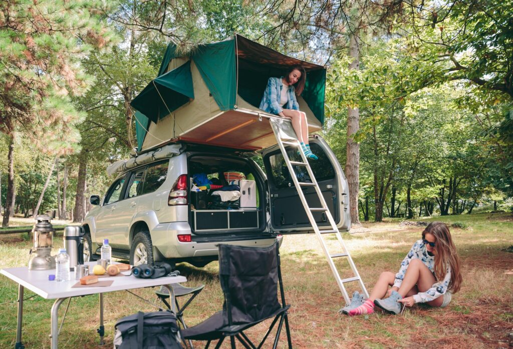 Woman in tent over 4x4 and other putting hiking boots