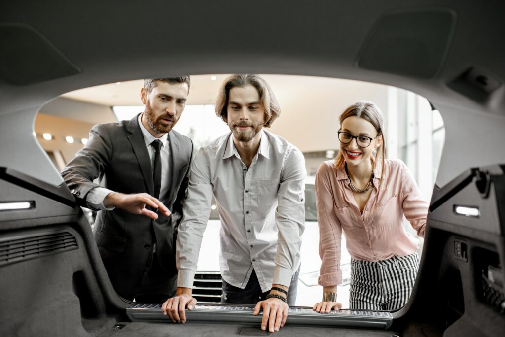 Salesman showing trunk of a new car in the showroom